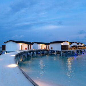 Stunning overwater bungalows lit up at twilight, providing a serene tropical getaway.